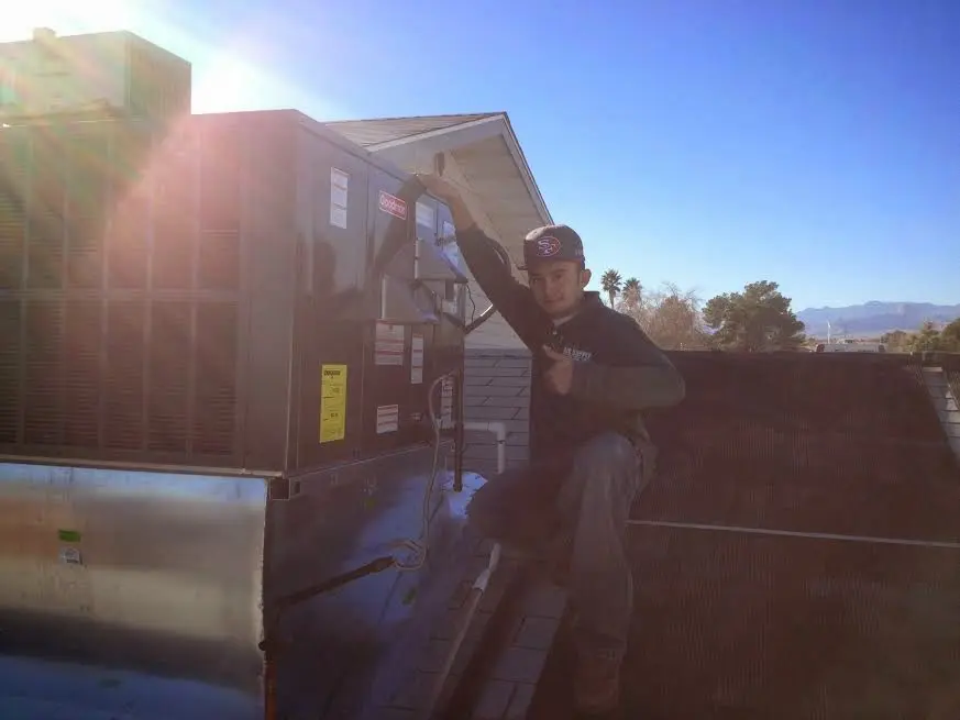 HVAC technician performing Heat Pump Repair on a rooftop unit in Mendota