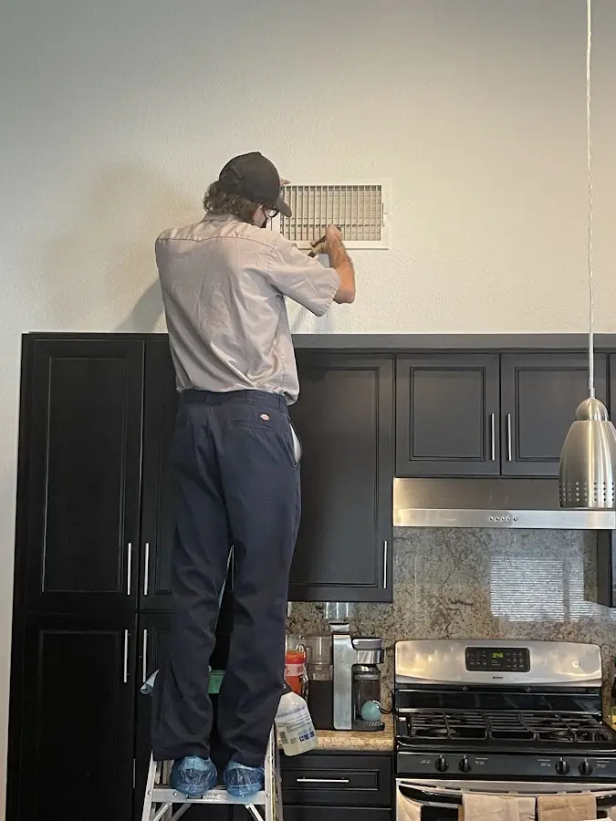 Technician inspecting an air vent during HVAC service in Mendota